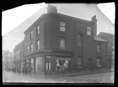 Black and white shop front with window display and people walking by